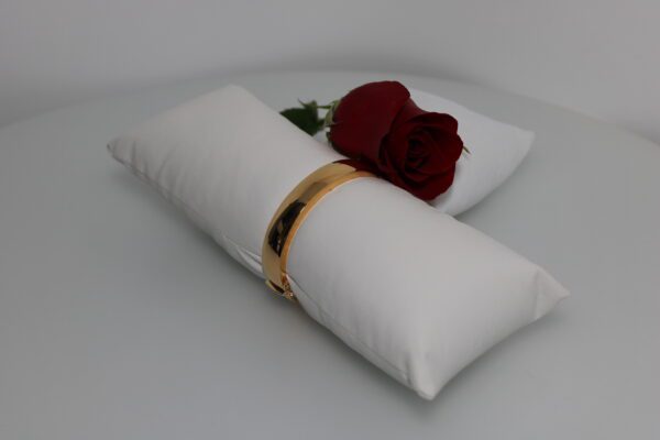 Elegant white napkin with a golden ring and a red rose on a plate.
