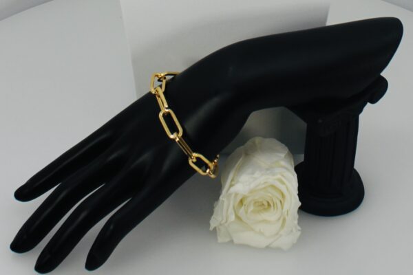 Elegant gold chain bracelet displayed on a black hand model with a white rose.