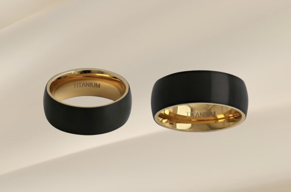 Two elegant black and gold rings on a smooth surface.