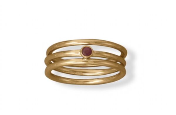 Gold ring with three bands and a small central red gemstone.
